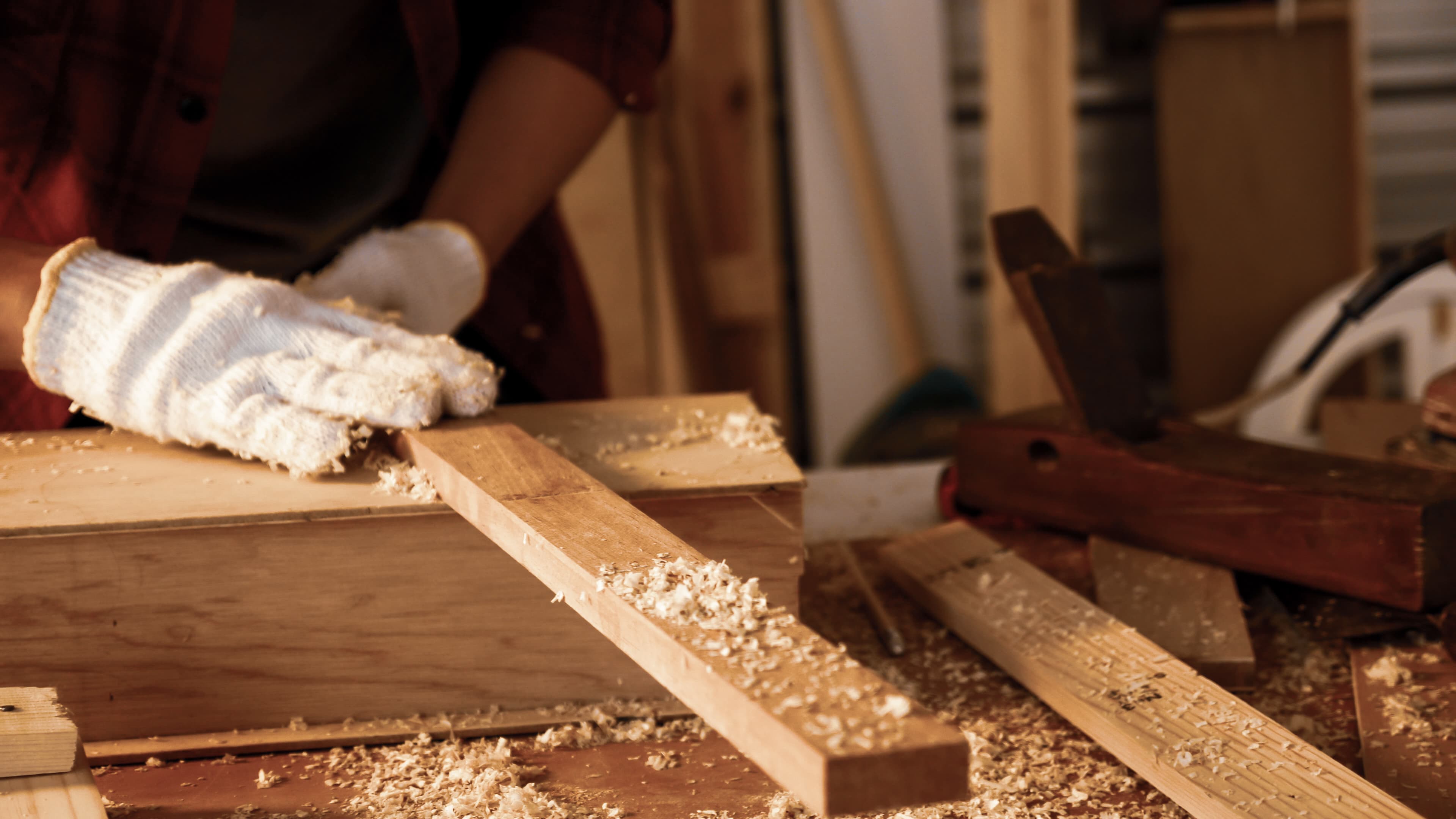 Hands shaping a piece of timber by hand.