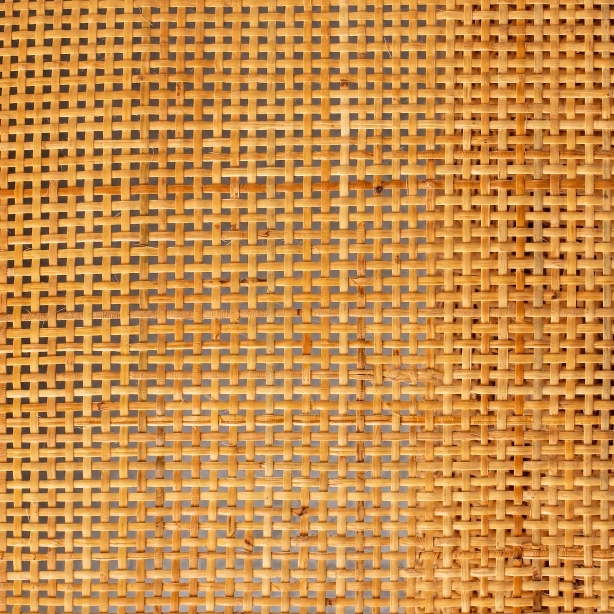 Front view of open cane weave, with small openings between horizontal and vertical strips.